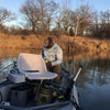 Kryptek hoodie wearing man with complete fishing gear, equipment, and boat