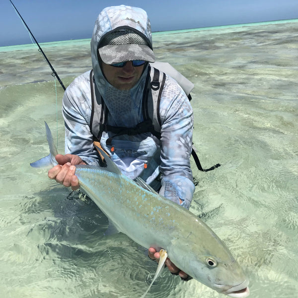 man catching fish while wearing kryptek hoodie on fly fishing.