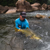 Angler with flat bill hat and blue sun shirt is catching a fish