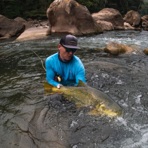 Angler with flat bill hat and blue sun shirt is catching a fish