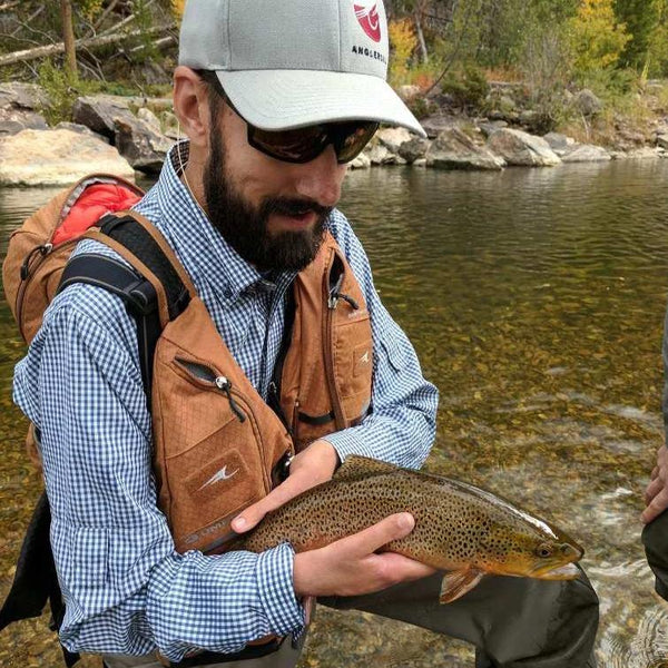 Professional fisher wearing Navy Gingham Shirt and complete fishing gear with a catch in hand.