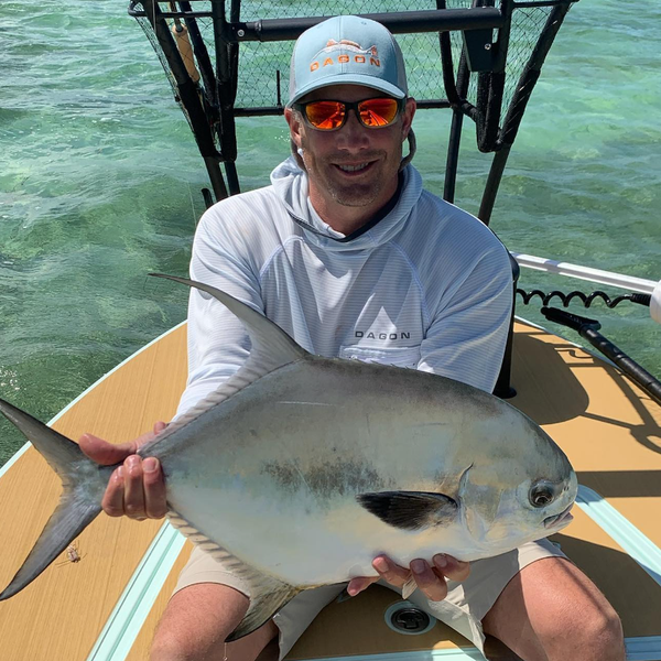 man in dagon apparel Embroidered blue Trucker Hat and sunshirt, with a gigantic catch in hands 