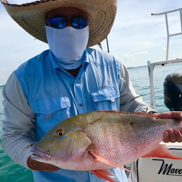 A seasoned angler with a big fish posing while wearing a blue shirt