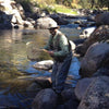 Man on water catching fishes, wearing wader, diggers, hat, sunglasses, and Dagon Pear Shirt 