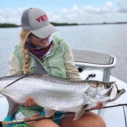 A professional seasoned angler Alyssa with a catch in hand smiling, wear Dagon special fishing apparel. 